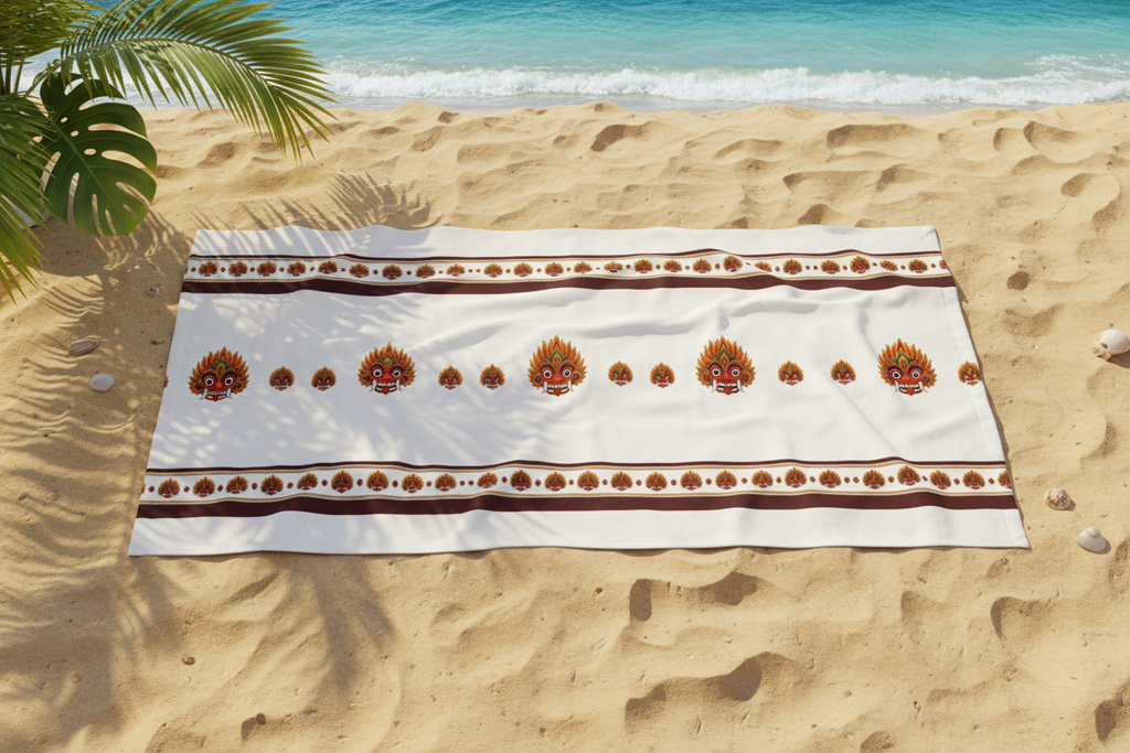 Raksha beach towel with Sri Lankan devil dance mask print laid on golden sand — Raksha Collection — Ceylon Culture Vibes